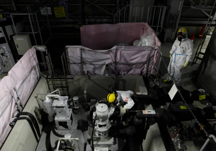 Employees of TEPCO wearing protective suits and masks are seen inside a radiation filtering  ALPS at tsunami-crippled Fukushima Daiichi nuclear power plant in Okuma town, Japan